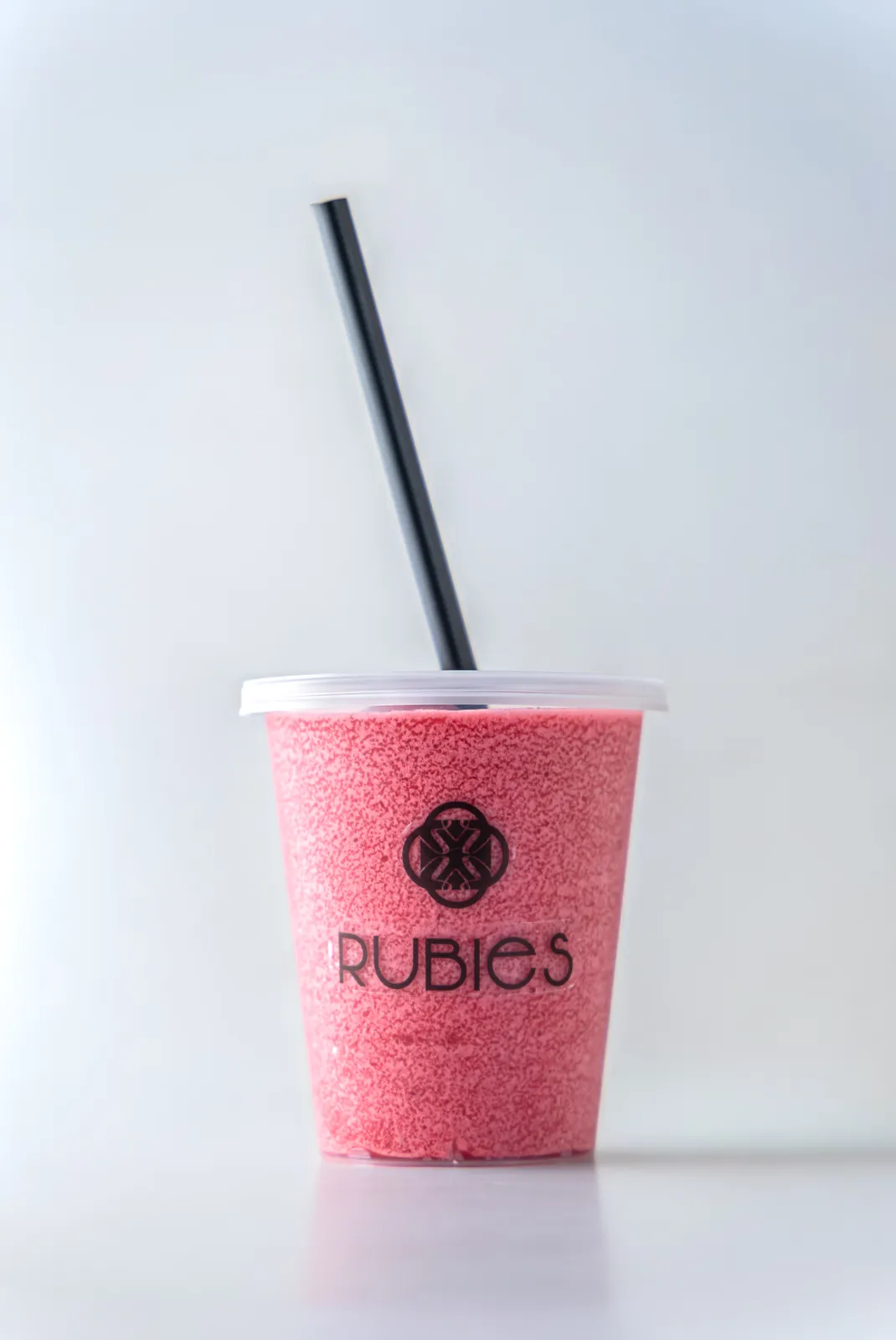 Clear Rubies cup with a thick pink blended frozen drink and a black straw